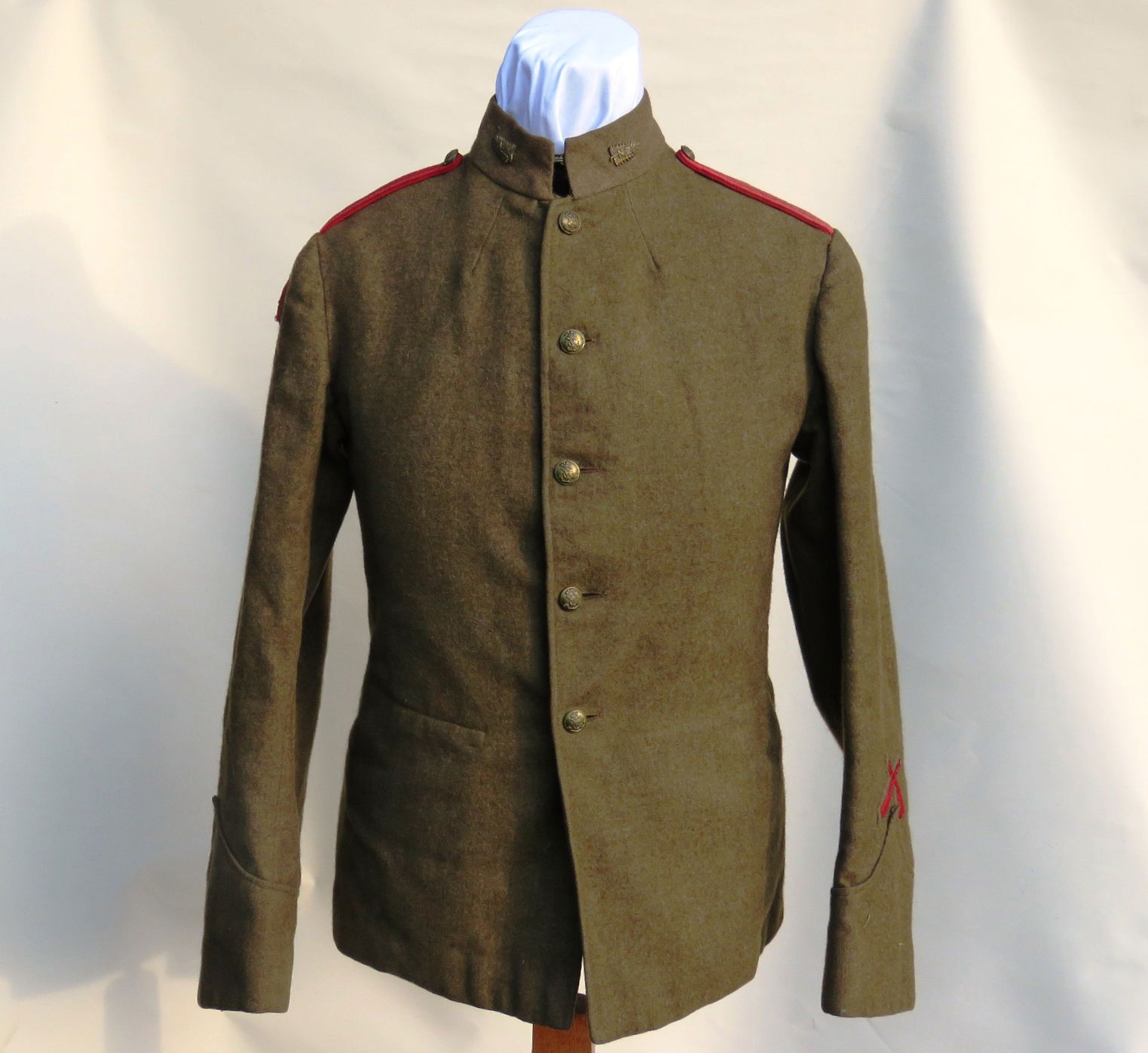 A King's Colonials Service Dress tunic for the New Zealand Troop of 'D' Squadron (British African) circa 1905-1910. The tunic has New Zealand fern brass collar badges, King's Colonials brass buttons, a scarlet King’s Crown at the top of the right sleeve for a Squadron Sergeant Major with a pair of holes in the tunic through which a New Zealand NCO's arm badge would have been attached, and a scarlet woven marksman badge at the bottom of the left cuff. The shoulders are fitted with thin scarlet cord straps (Photographs courtesy of Medallion Militaria).