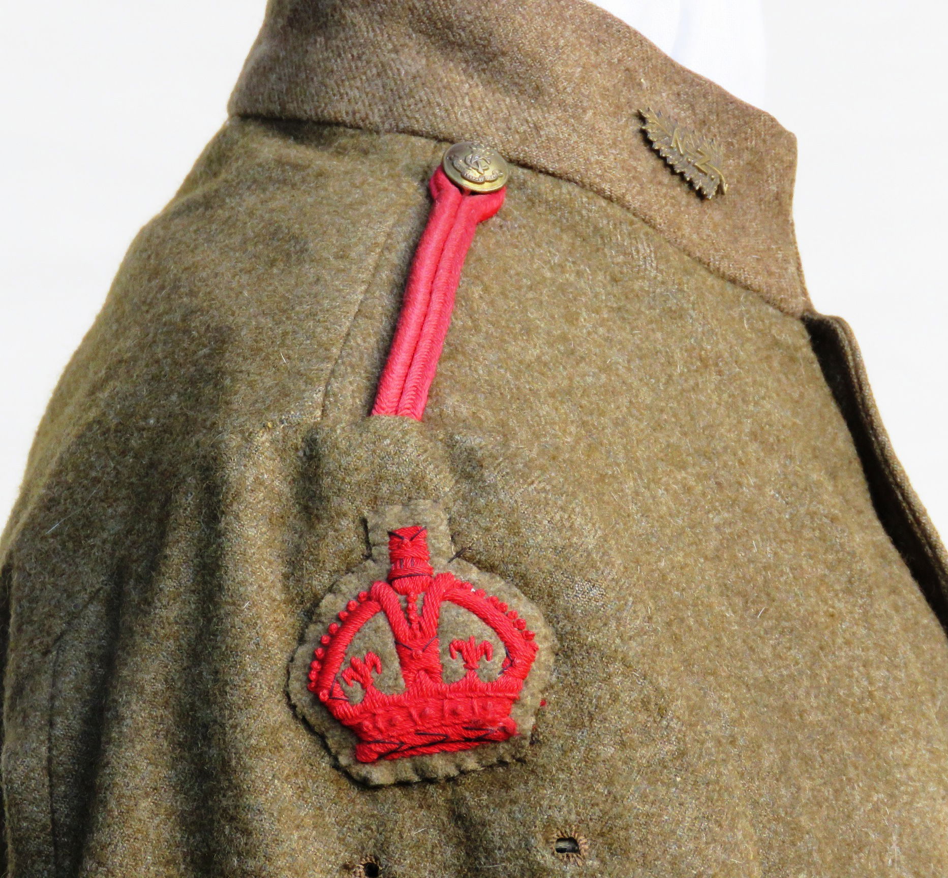A King's Colonials Service Dress tunic for the New Zealand Troop of 'D' Squadron (British African) circa 1905-1910. The tunic has New Zealand fern brass collar badges, King's Colonials brass buttons, a scarlet King’s Crown at the top of the right sleeve for a Squadron Sergeant Major with a pair of holes in the tunic through which a New Zealand NCO's arm badge would have been attached, and a scarlet woven marksman badge at the bottom of the left cuff. The shoulders are fitted with thin scarlet cord straps (Photographs courtesy of Medallion Militaria).
