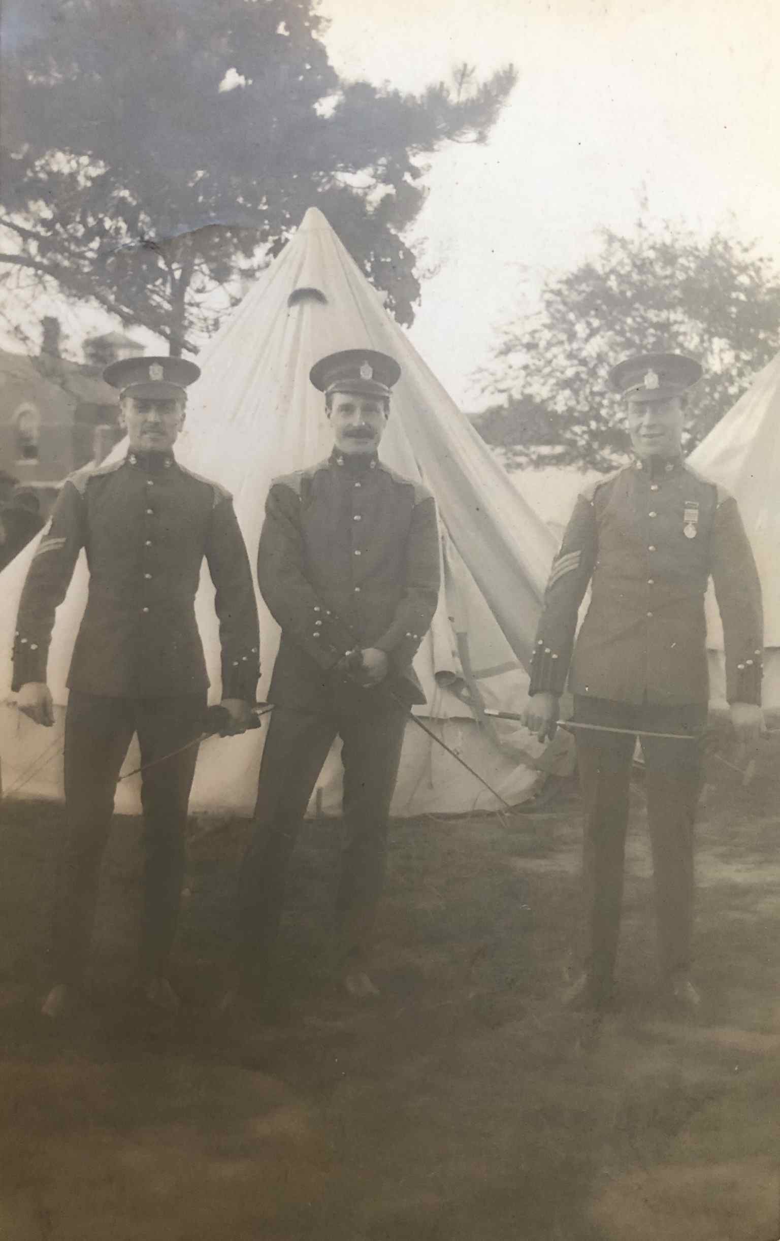 Photograph of a Serjeant, Corporal and a Private of the King Edward's Horse in Undress uniform each wearing a King Edward's Horse headdress and 'B' Squadron (British American) collar badges circa 1912. The fact that they are wearing King's Colonials collar badges suggesting that all three members were from the pre-1910 King's Colonials.  The Serjeant is wearing a Queen's South African medal with multiple bars. The Serjeant and Corporal are both wearing King Edward's Horse headdress badges and NCOs arm badges above their rank chevrons.