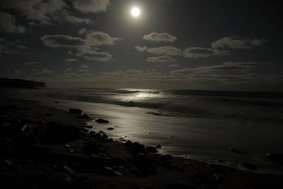 Un hombre caminaba por la playa en una noche de luna llena