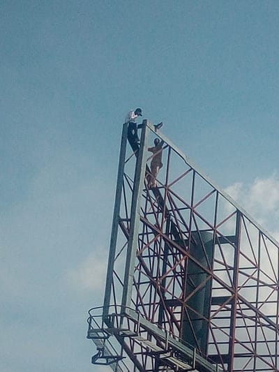 Man Climbs Billboard To Protest Against Buhari, Hunger In Adamawa (Photos)