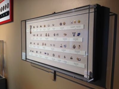 Wall-mounted display case featuring various artifacts, labeled for identification, showcasing custom acrylic fabrication for museum presentations.