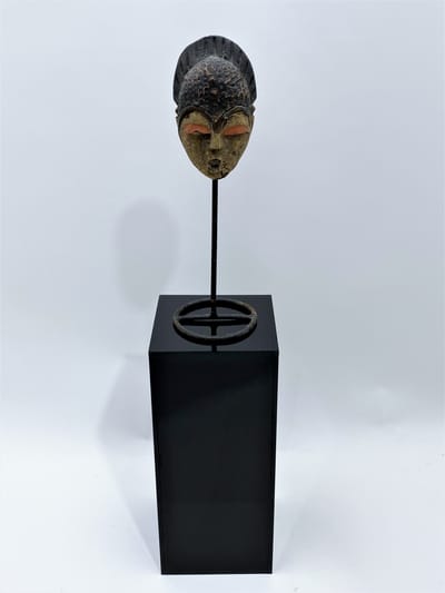 African tribal mask displayed on a modern black acrylic pedestal, emphasizing museum-quality display for art and collectibles.