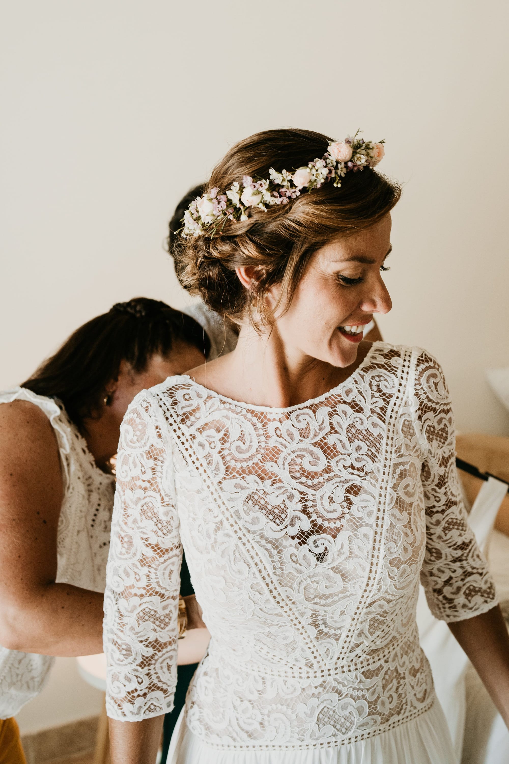 Mariée qui enfile sa robe de mariée en dentelle