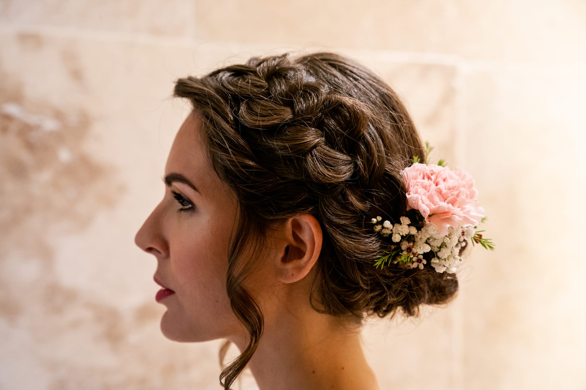 Coiffure mariage chignon bas flou avec tresse et barrette de fleur en Gypsophile et Rose