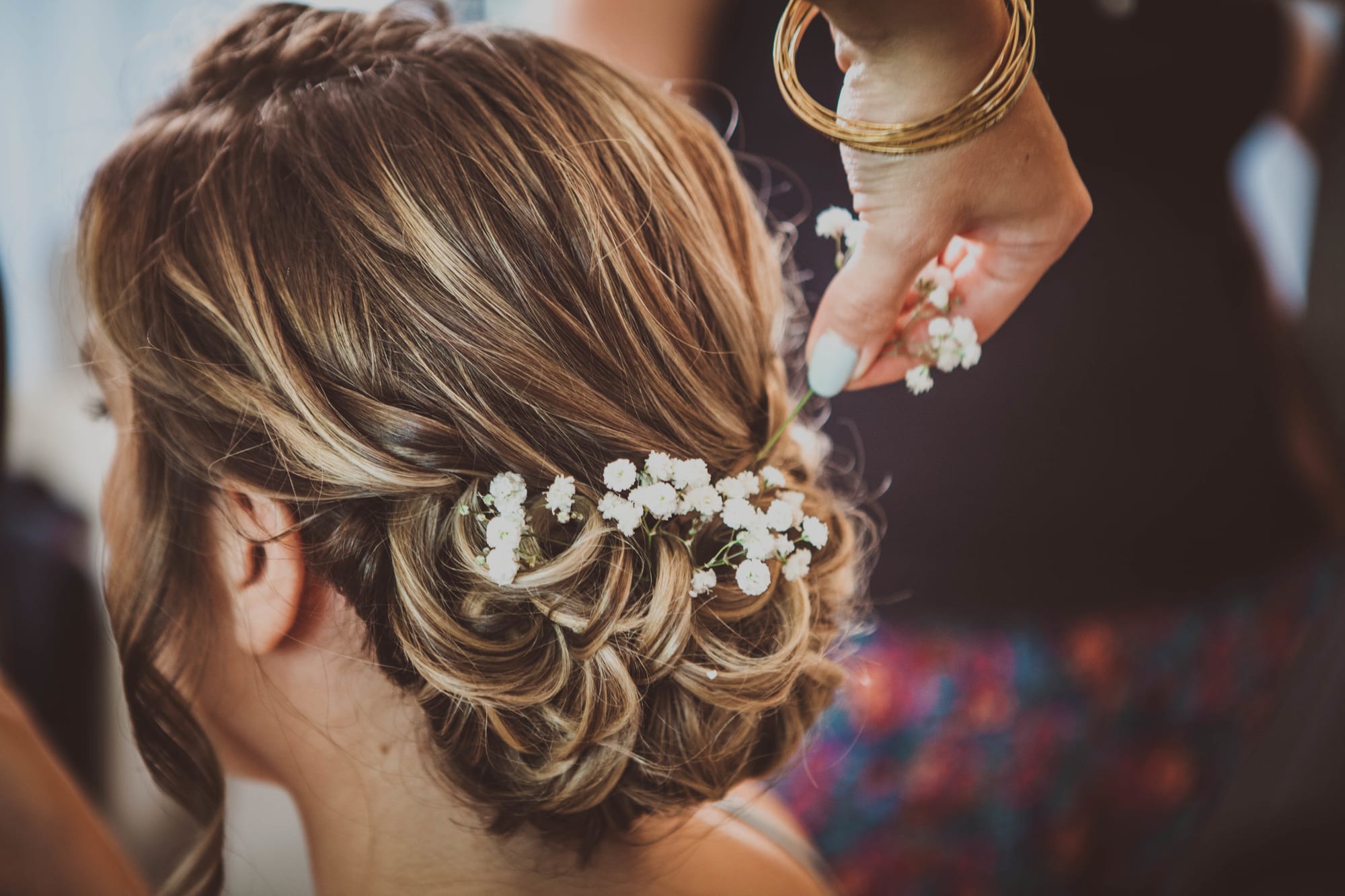 Mise en place de gypsophile sur un chignon bas et tressé - coiffure mariée