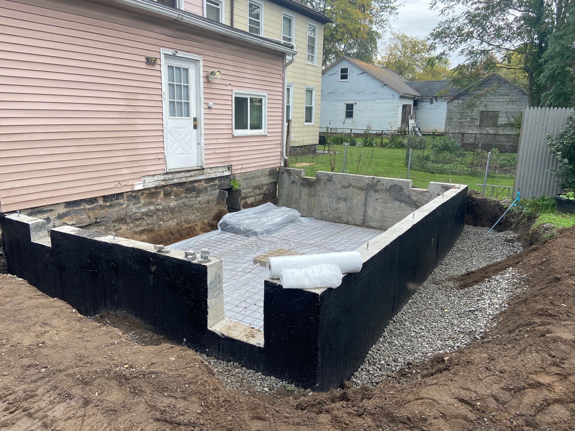 Excavation, footings, walls & waterproofing of a poured concrete foundation.