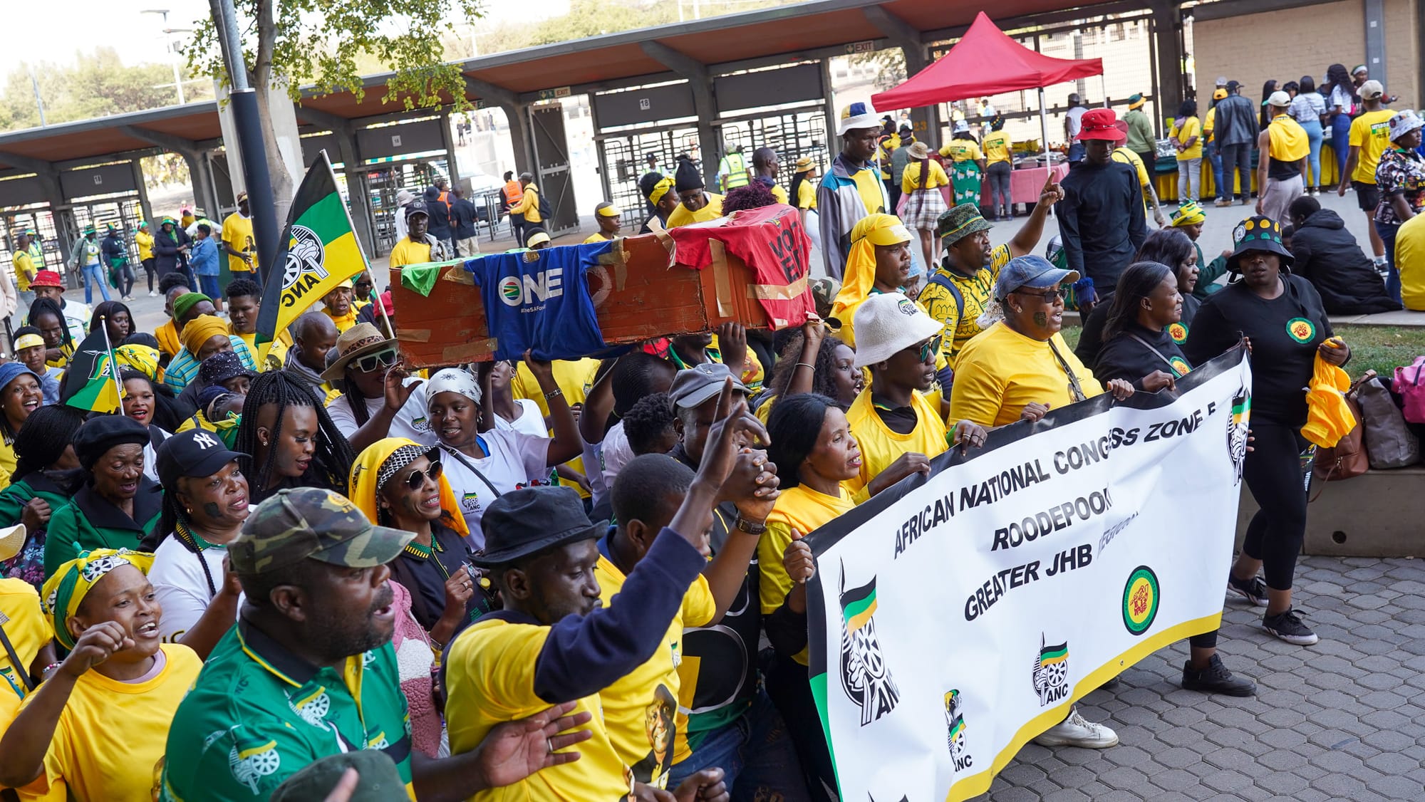 ANC supporters carrying a coffin wrapped in different political shirts