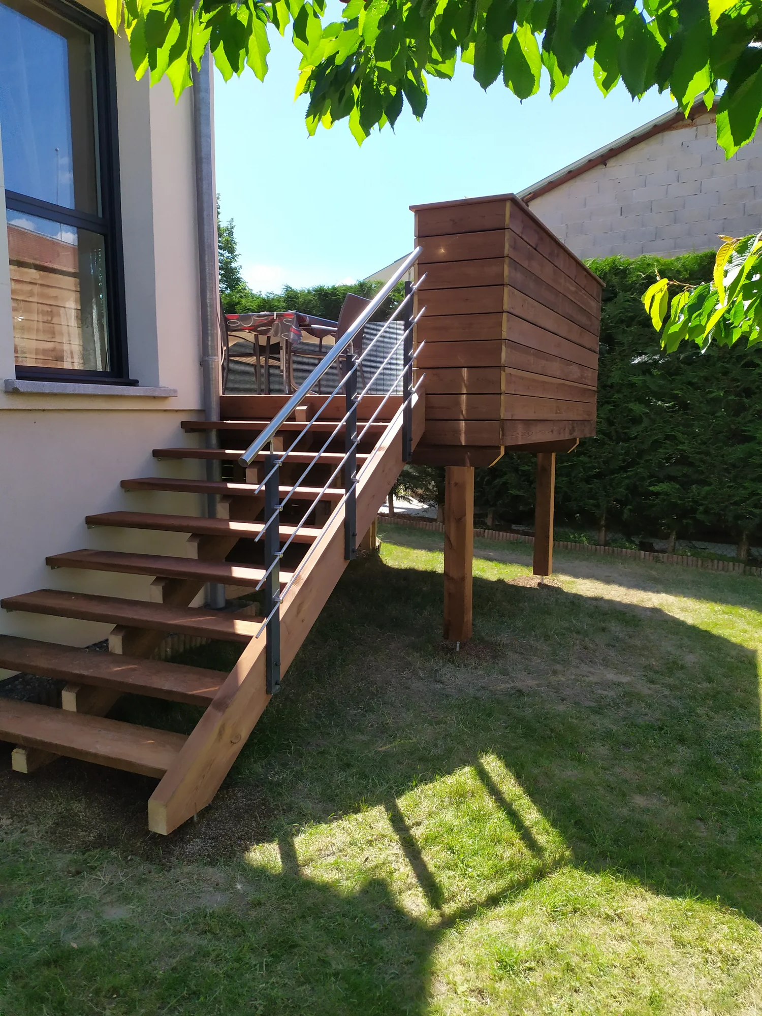 Terrasse en pin autoclave marron, bac à plantes et escalier bois