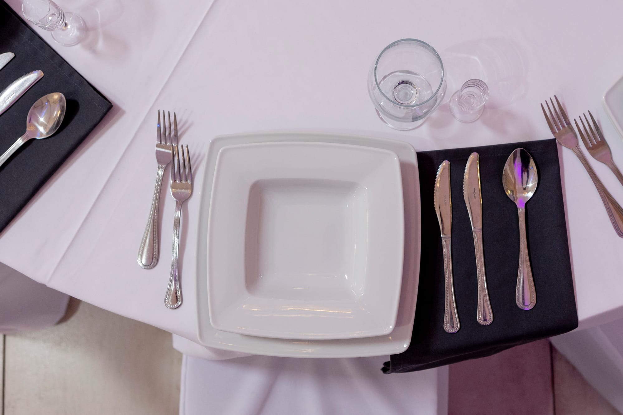 Srebrne sztućce i kwadratowe talerze.