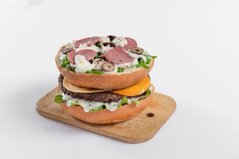 Wild pizza burger.....برجر الدجاج او اللحم المحشو بالجبنة الموتزريلا مع فطيرة البيتزا والزيتون الأسود والمشروم الطازج والفلفل الألوان وقطع البصل المشوية ومكععبات الطماطم وقطع البيبروني والجرجير الطازج مع صوص وايد المميز بالخيار الطازج