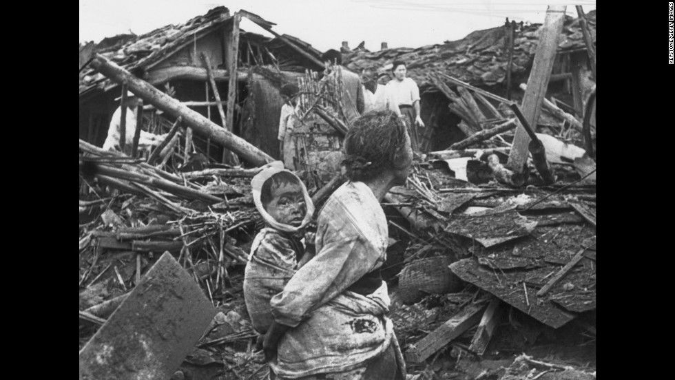 Korean War, A woman and child wander among debris in Pyongyang, North Korea, after an air
