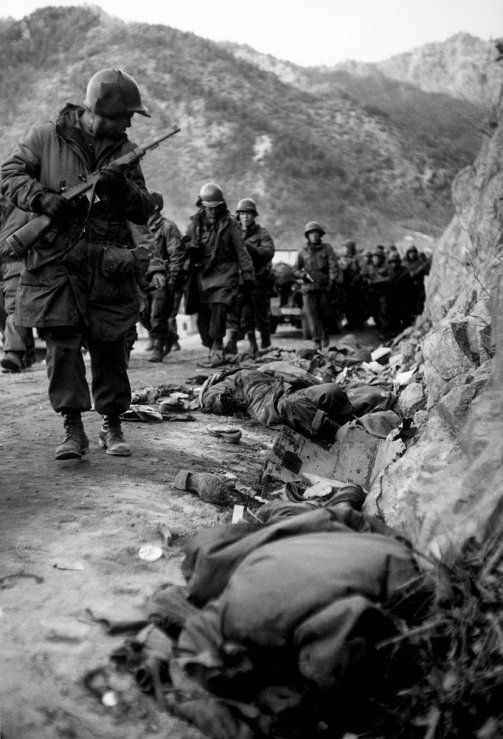 1950  Korean War Marines marching past bodies,