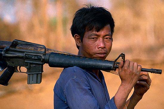 Vietnam War  militiaman carrying an M16 rifle over his shoulder heads along a road towards the Cambodian border