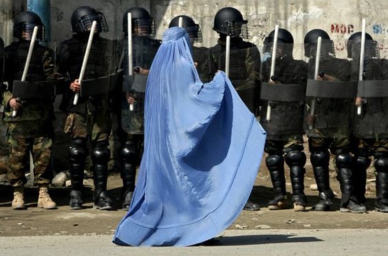 Afghanistan War February 23, 2007, A woman walks past riot police outside a gathering in Kabul's stadium