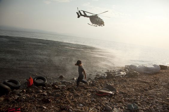 Iraq War Frontex helicopter patrols over a Syrian child who has just arrived at a beach on the Greek island of Lesbos, Aug. 10, 2015