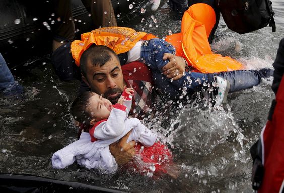 Iraq War Syrian refugee holds on to his children as he struggles to walk off a dinghy into Lesbos after crossing the Aegean Sea from Turkey, Sept. 24, 2015