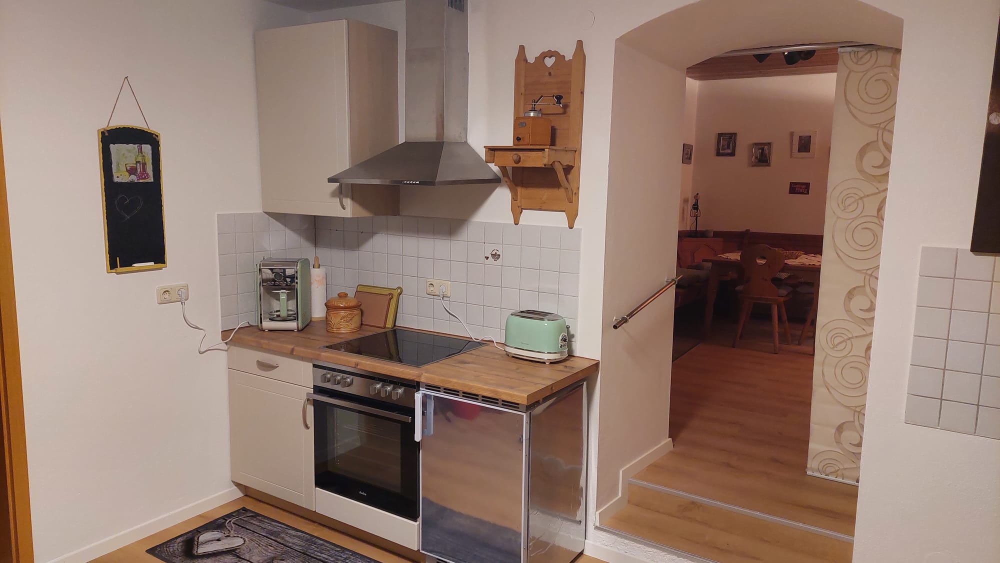 Küche mit Kühlschrank, Backofen und Cerankochfeld, Blick ins Wohnzimmer